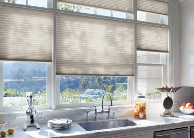 Sunlit kitchen sink with beige cellular shades