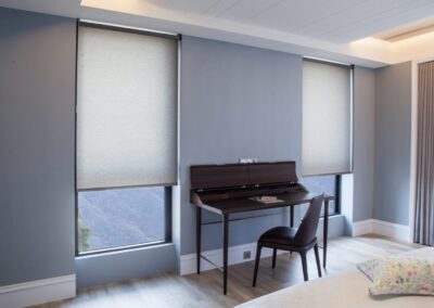 Upright piano and chair between shaded windows