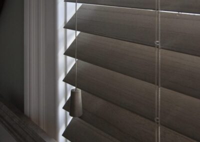 Close-up of gray wooden window blinds with cords
