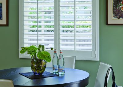 Round dining table by plantation shutters