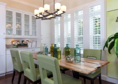 Sunlit dining room with green chairs